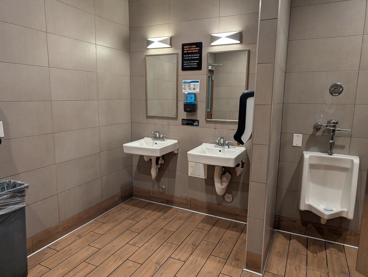 Wide view of the clean, tiled interior with modern lighting and sinks.